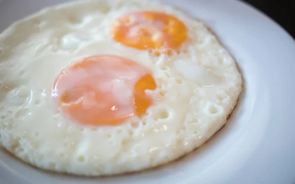 Two fried egg on the white plate on breakfast table — Stock Photo, Image