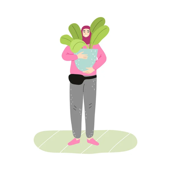 Молодая улыбающаяся мусульманка в хиджабе и спортивной одежде держит растение в горшке — стоковый вектор