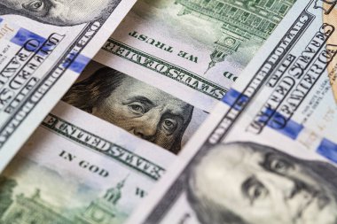 Benjamin Franklin 100 dolarlık banknotları dikizliyor.