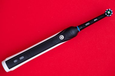  Elektrikli diş fırçasının yakın plan Oral-B Cross Action PRO 750 siyah baskı kırmızı zemin üzerine
