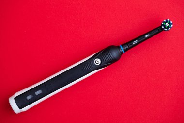  Elektrikli diş fırçasının yakın plan Oral-B Cross Action PRO 750 siyah baskı kırmızı zemin üzerine