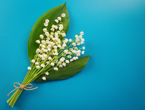 Beautiful white lilies of the valley on a turquoise background. Minimalist background with Lily of the valley colors.