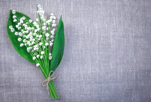 Top view of a bouquet of lilies of the valley with leaves on a gray matting background. Lilies of the valley with a copy of space.