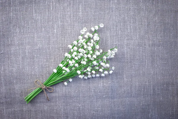 Top view of a bouquet of lilies of the valley on a gray matting background. Lilies of the valley with a copy of space.