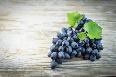 Eski ahşap arka planda yeşil yapraklı bir demet üzüm, yatay olarak.,