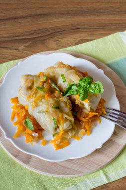 Beyaz tabakta içi doldurulmuş lahana yaprakları, yakın plan.