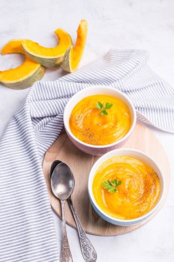 Arka planda parlak kâselerdeki lezzetli balkabağı çorbası. Dikey olarak yakın plan. Vejetaryen yemeği..