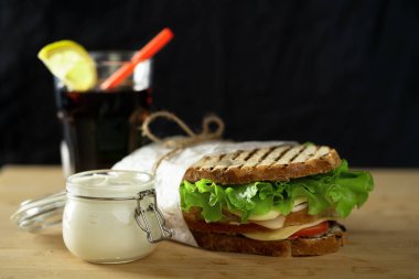 ahşap tahta üzerinde sos ve meşrubat ile iki kulüp sandviç.