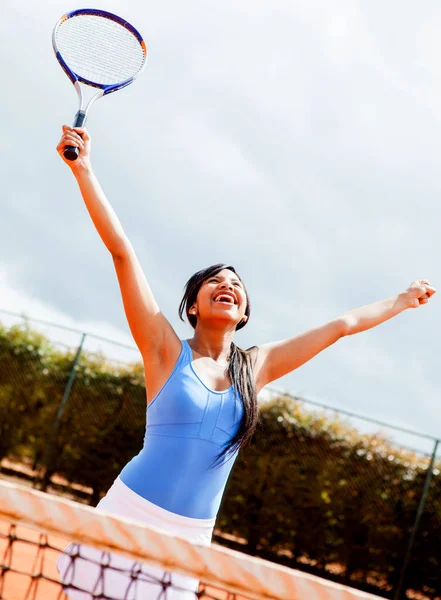 Female tennis player winning with arms up