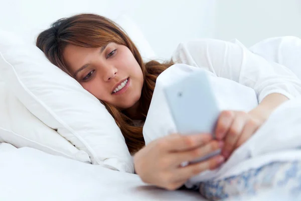 Young woman using smartphone in bed