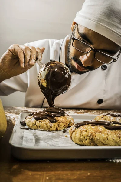 Male chef pouring hot chocolate on cookies