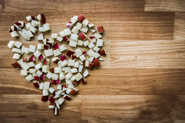 Heart symbol by apple pieces on wood table