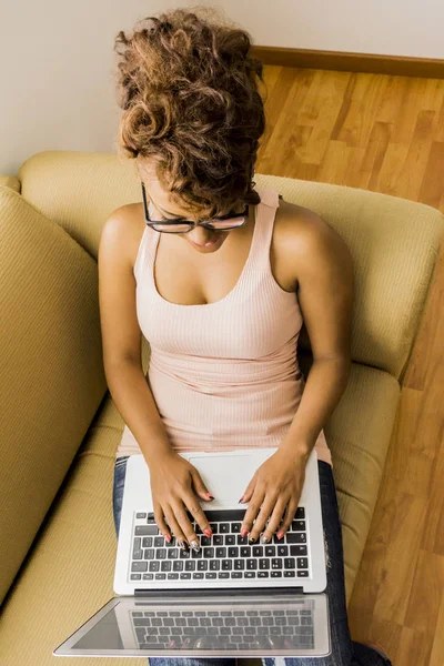 Young woman working on laptop at the couch