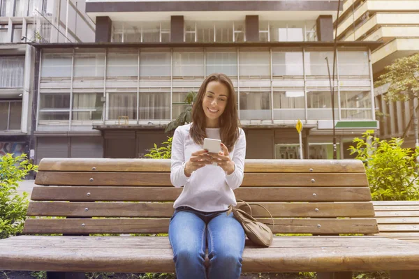 Single woman sitting and texting outdside in the street