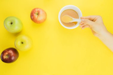 Rosh Hashanah, elma ve sarı zemin üzerine bal fincan. bal ve elma için eller ulaşmak.