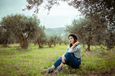 Genç tatlı kız zeytin bahçesinin ortasında dinleniyor.