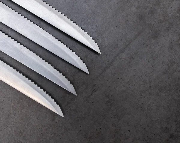Cuchillos dentados sobre una mesa gris oscura — Foto de Stock