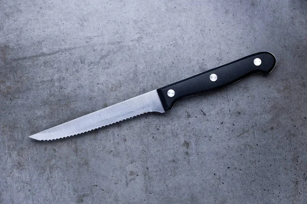 Cuchillo dentado sobre una mesa gris oscura — Foto de Stock