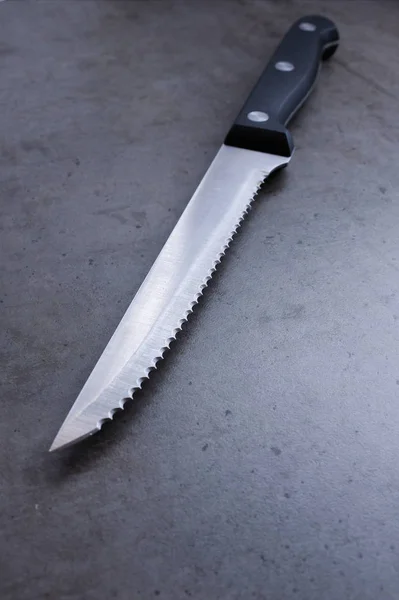 Зазубренный нож на тёмно-сером столе — стоковое фото