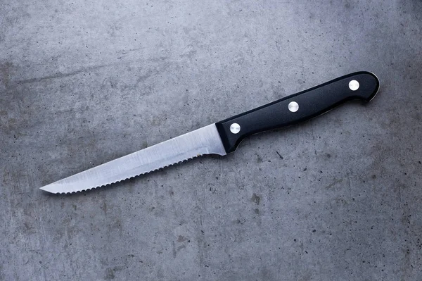 Serrated knife on a dark gray table Stock Photo