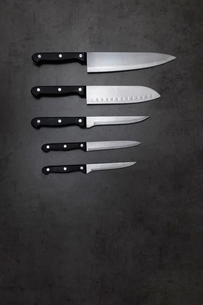 Set di coltelli su un tavolo grigio scuro Immagine Stock