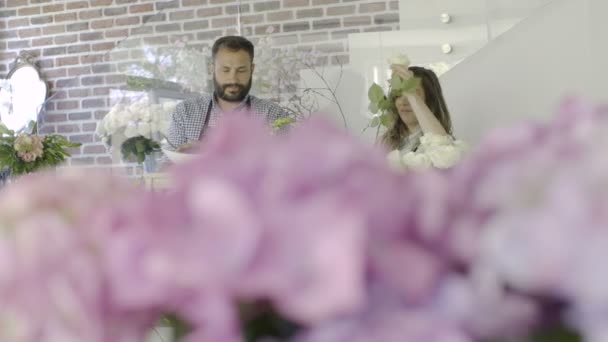 Para piękny kwiaciarni uśmiechający się dokonać dekoracji w kwiaciarni — Wideo stockowe