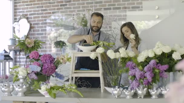 Çiçekçi çift gülümseyen genç aile çiçekçide çalışmak — Stok video