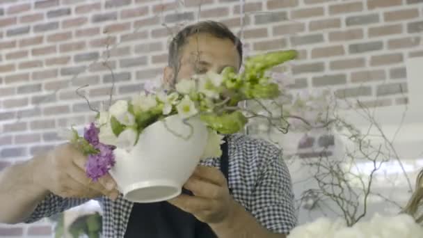 Крупним планом вид на двох флористів, які готують аранжування в квітковому магазині білих троянд — стокове відео