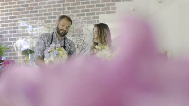 Twee jonge bloemisten werken bij bloemen winkel. — Stockvideo