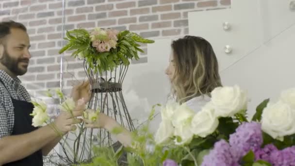 Sorridente giovani fioristi coppia fanno una decorazione floreale in un negozio di fiori — Video Stock