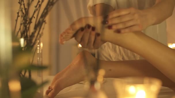 Wanita muda pijat kaki di salon spa kecantikan, tutup. latar belakang lilin — Stok Video