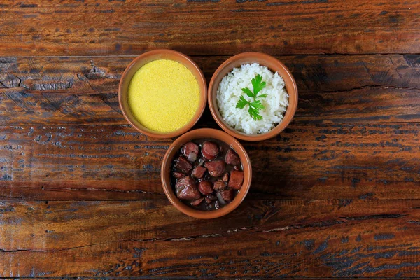 Brazilian feijoada, traditional dish of the Brazilian cuisine, on wooden table. top view