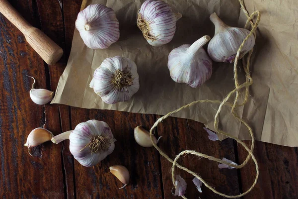 Garlic bulbs on packing paper, on rustic wooden table. Closeup of garlic bulbs.