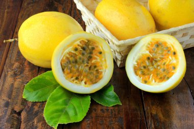 sarı tutku meyve sepeti ve tutku meyve içinde yaprak ile ahşap masa üzerinde ikiye böldüm. Üstten görünüm