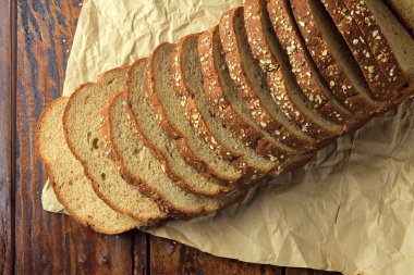 Organik ekmek dilimlenmiş kepekli yulaf ve keten tohumu kağıt üzerinde ahşap masa üzerinde oluşur. Sağlıklı Diet.Top görünümü