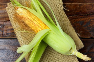 rustik ahşap masa üzerinde rustik kumaş üzerine Ham Mısır kulak. metin için yer. Üstten görünüm