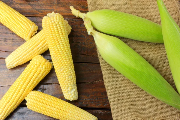 ham Mısır çiftliğinde rustik ahşap masa üzerinde rustik bez üzerinden hasat, kulak. üstten görünüm