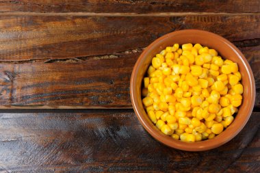 Rustik ahşap masa üzerinde seramik tencere içinde ham mısır taneleri. metin için yer. Üstten görünüm.