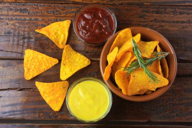 Çeşitli soslar yanındaki ahşap masa üzerinde seramik kase cips mısır cipsi yerleştirilir