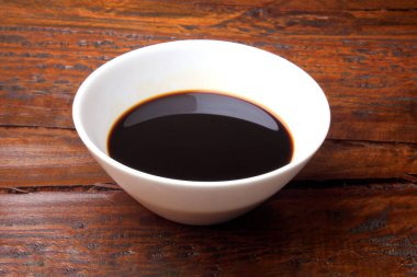 koyu soya sosu rustik ahşap masaya izole bir beyaz seramik kase