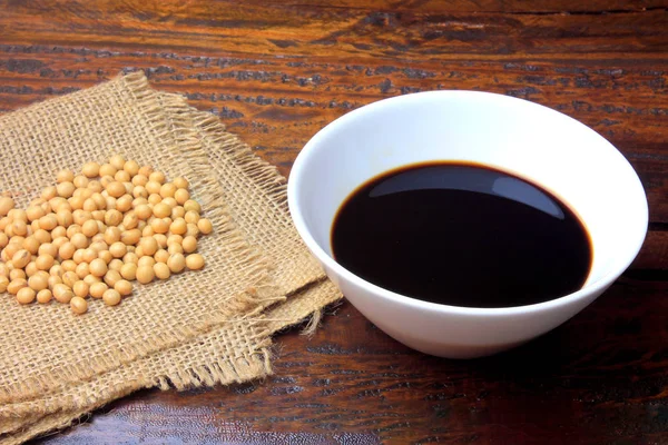 Soya fasulyesi rustik ahşap masa üzerinde seramik bir kasede koyu soya sosu ile