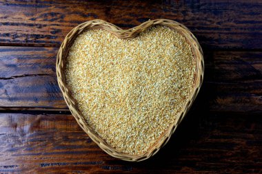 Susam rustik ahşap masa, üstten görünüm izole kalp şeklinde sepet içinde.