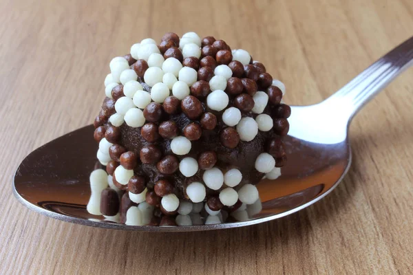 Brigadeiro (Brigadier), süße Schokolade, typisch für die brasilianische Küche, mit Partikeln überzogen, vor einem hölzernen Hintergrund. — Stockfoto