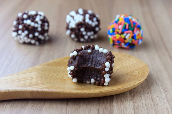 Brigadeiro (Brigadier), süße Schokolade, typisch für die brasilianische Küche, mit Partikeln überzogen, vor einem hölzernen Hintergrund. — Stockfoto