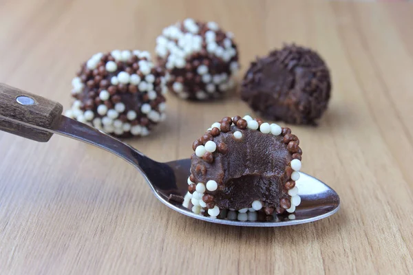 Brigadeiro (brigadier), sweet chocolate typical of Brazilian cuisine covered with particles, in a wooden background. — Stock Photo, Image