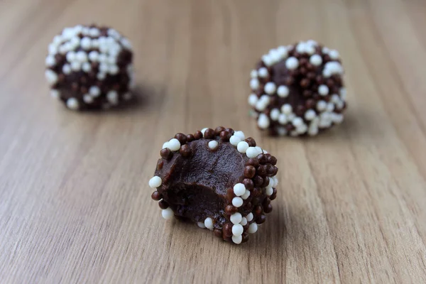 Brigadeiro (Brigadier), süße Schokolade, typisch für die brasilianische Küche, mit Partikeln überzogen, vor einem hölzernen Hintergrund. — Stockfoto