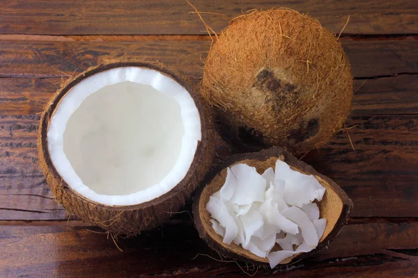 Свіжі кокосові пластівці та чіпси, поміщені в кору, ізольовані на сільському дерев'яному фоні — стокове фото