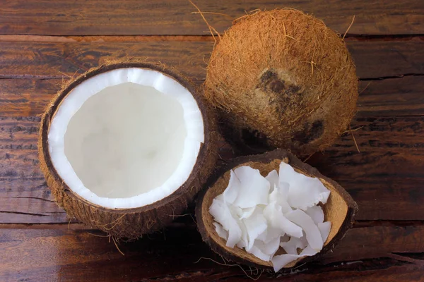 Hojuelas y virutas frescas de coco colocadas en corteza aislada sobre fondo rústico de madera —  Fotos de Stock