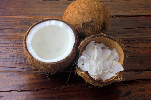 Hojuelas y virutas frescas de coco colocadas en corteza aislada sobre fondo rústico de madera —  Fotos de Stock