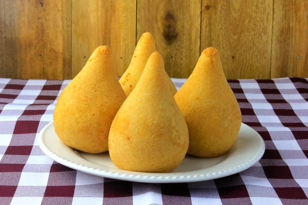 Coxinha no prato, lanches tradicionais da culinária brasileira recheados com frango, em mesa de madeira rústica — Fotografia de Stock